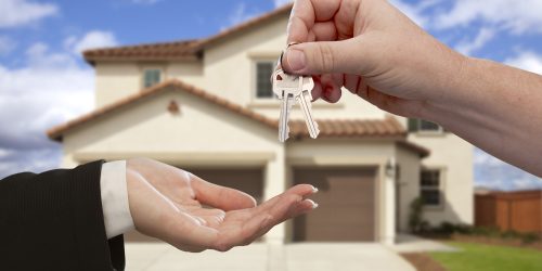 Handing Over the House Keys in Front of a Beautiful New Home.